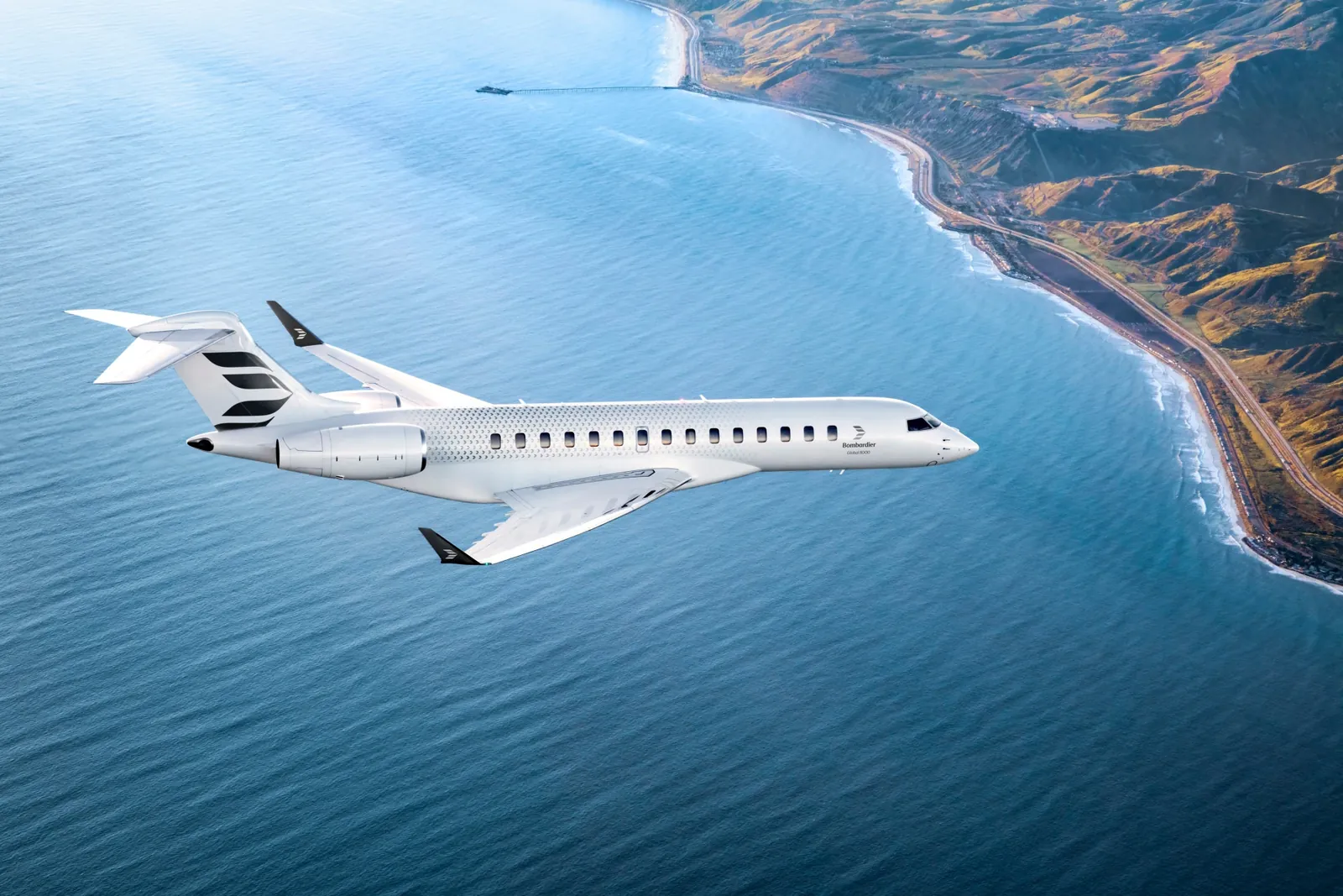 Bombardier Global 8000 in flight over the sea along a steep coastline