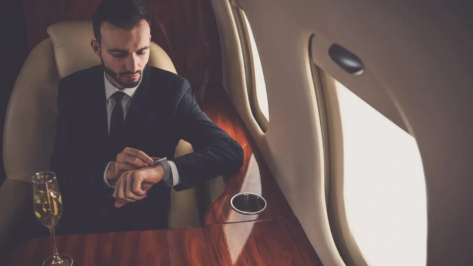 A businessman checks his watch in the cabin of a private jet