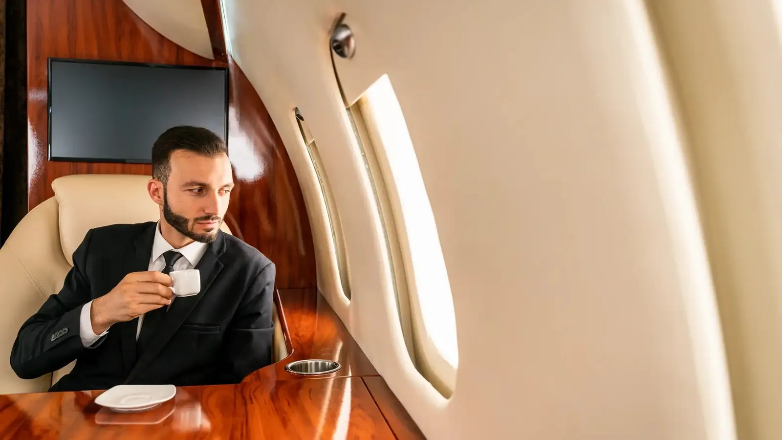 A passenger with a coffee in the cabin of a private jet