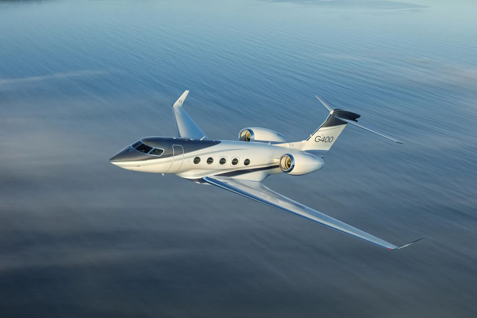 Gulfstream G400 business jet in flight over calm blue water