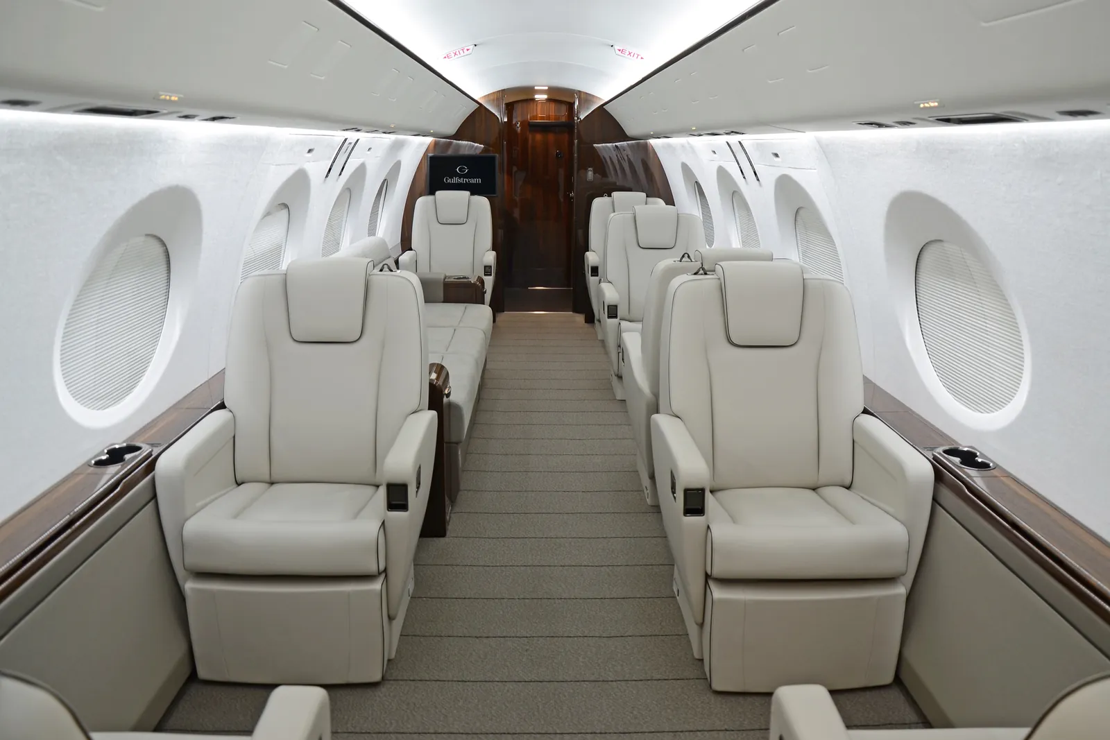 Outfitted cabin of the Gulfstream G400 with cream leather seats, a divan and dark wood veneer