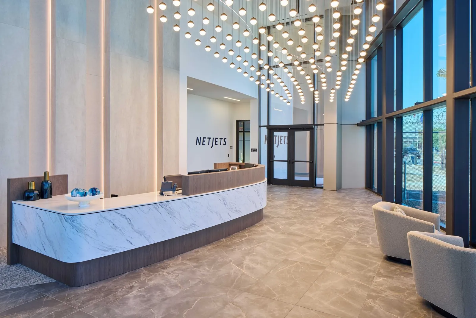 Reception desk in the lobby of the NetJets terminal in Las Vegas beneath a ceiling of pendant lights