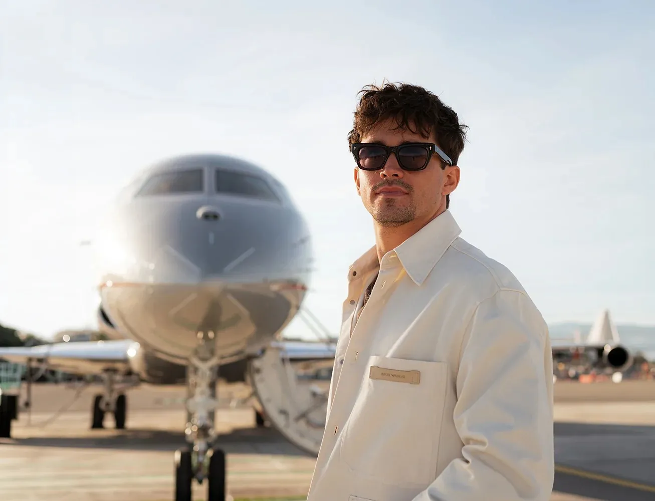 Charles Leclerc, VistaJet brand ambassador, on the apron in front of a silver VistaJet business jet
